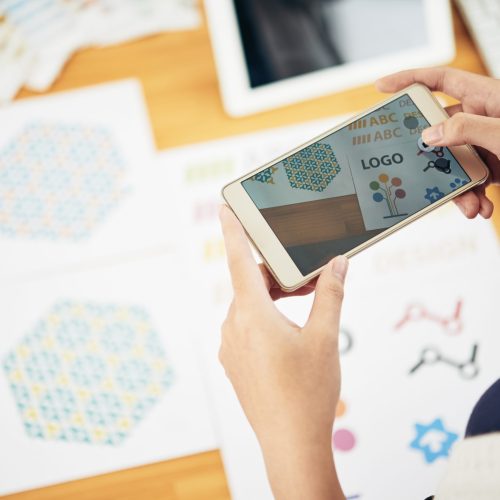 Close-up of woman photographing logotype on her phone